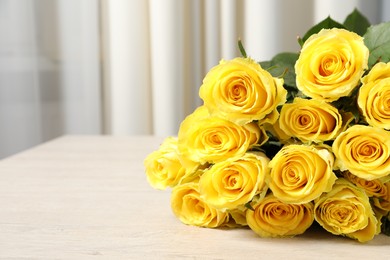 Beautiful bouquet of yellow roses on wooden table indoors, closeup. Space for text