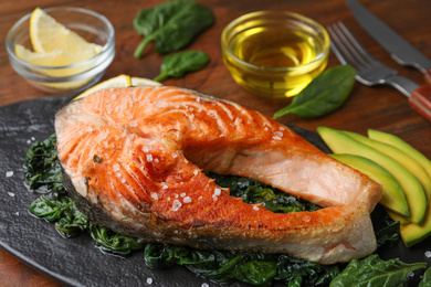 Photo of Tasty salmon with spinach served on table, closeup