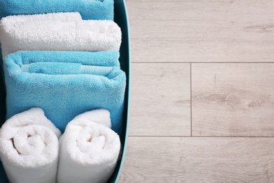 Photo of Laundry basket with clean towels on wooden floor