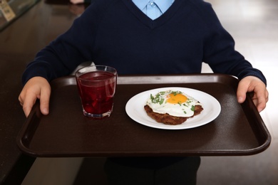 Boy holding tray with healthy food in school canteen, closeup