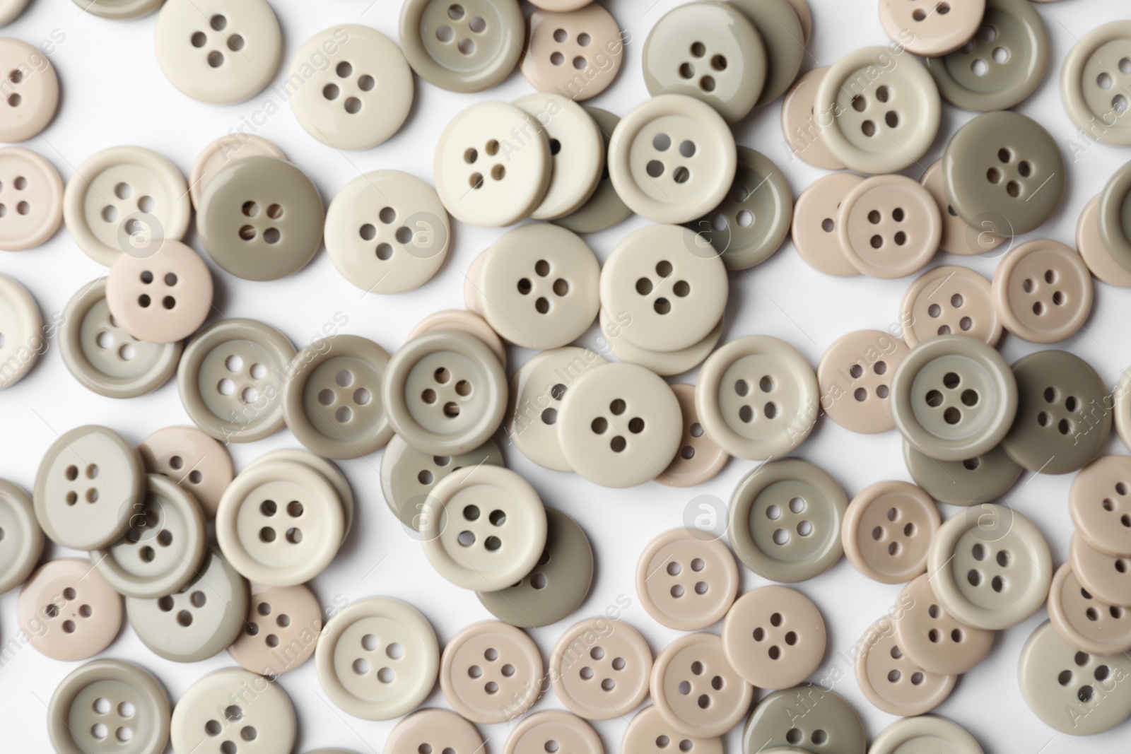 Photo of Many grey sewing buttons on white background, closeup