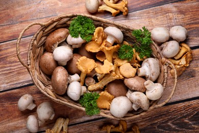 Basket with different mushrooms on wooden table, flat lay