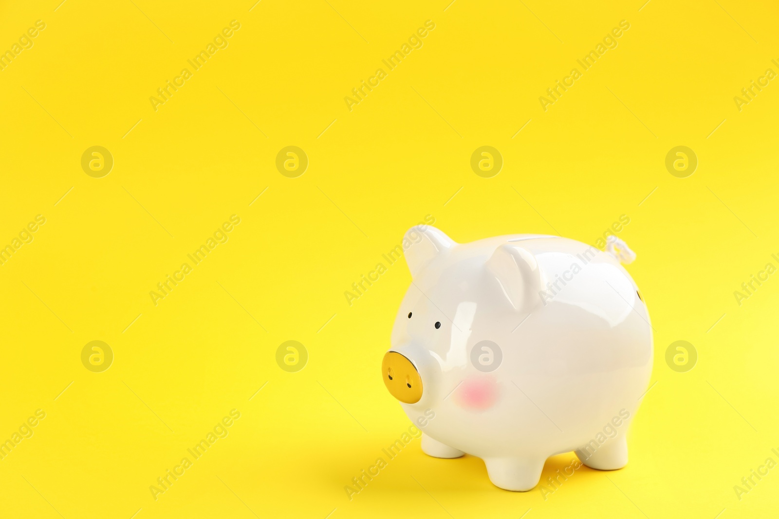 Photo of White piggy bank on yellow background. Space for text