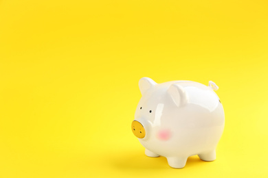 Photo of White piggy bank on yellow background. Space for text