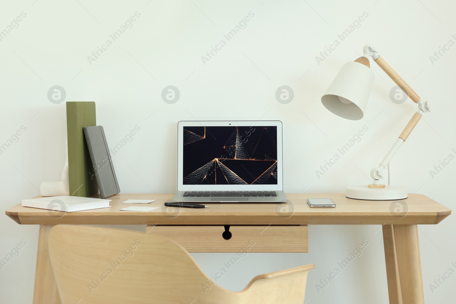 Photo of Cozy workspace with laptop, smartphone and lamp on wooden desk at home