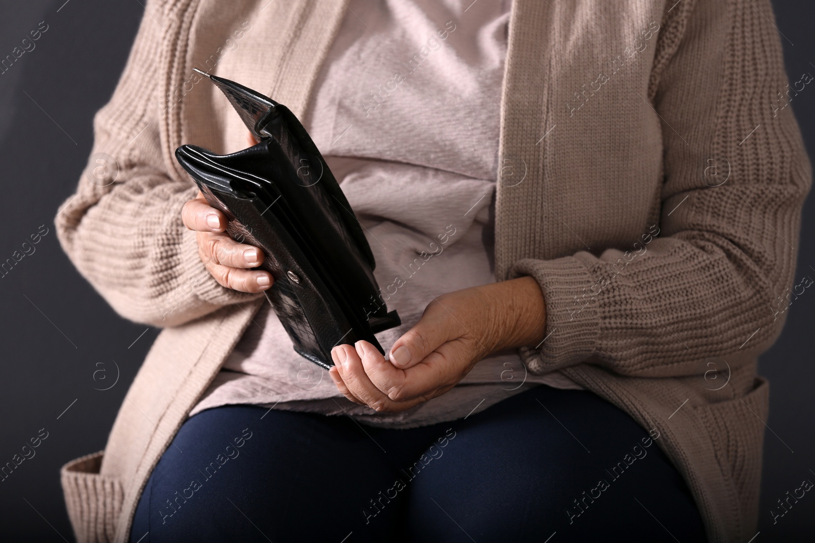 Photo of Poor elderly woman with empty wallet on dark background, closeup
