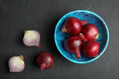 Bowl with ripe red onions on table, top view