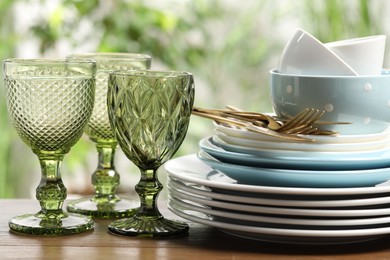 Photo of Beautiful ceramic dishware, glasses and cutlery on wooden table outdoors