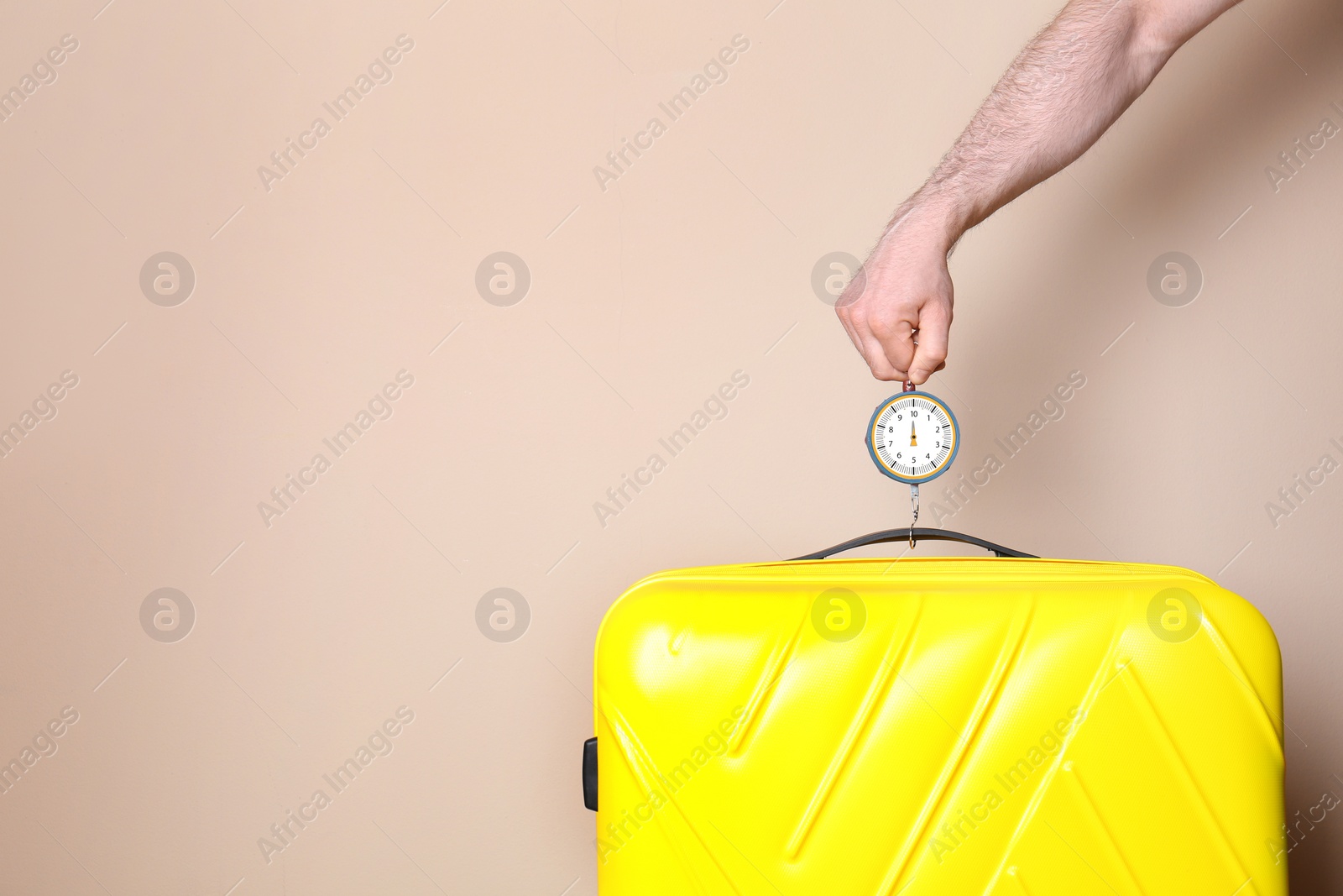 Photo of Man weighing stylish suitcase against color background, closeup. Space for text