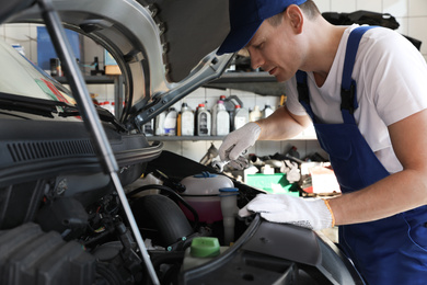 Professional auto mechanic fixing modern car in service center