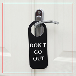 Closed door with sign DON'T GO OUT on handle. Stay at home during coronavirus quarantine