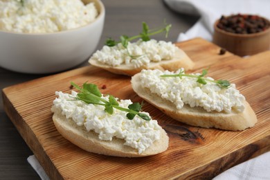 Photo of Bread with cottage cheese and microgreens on wooden table, closeup
