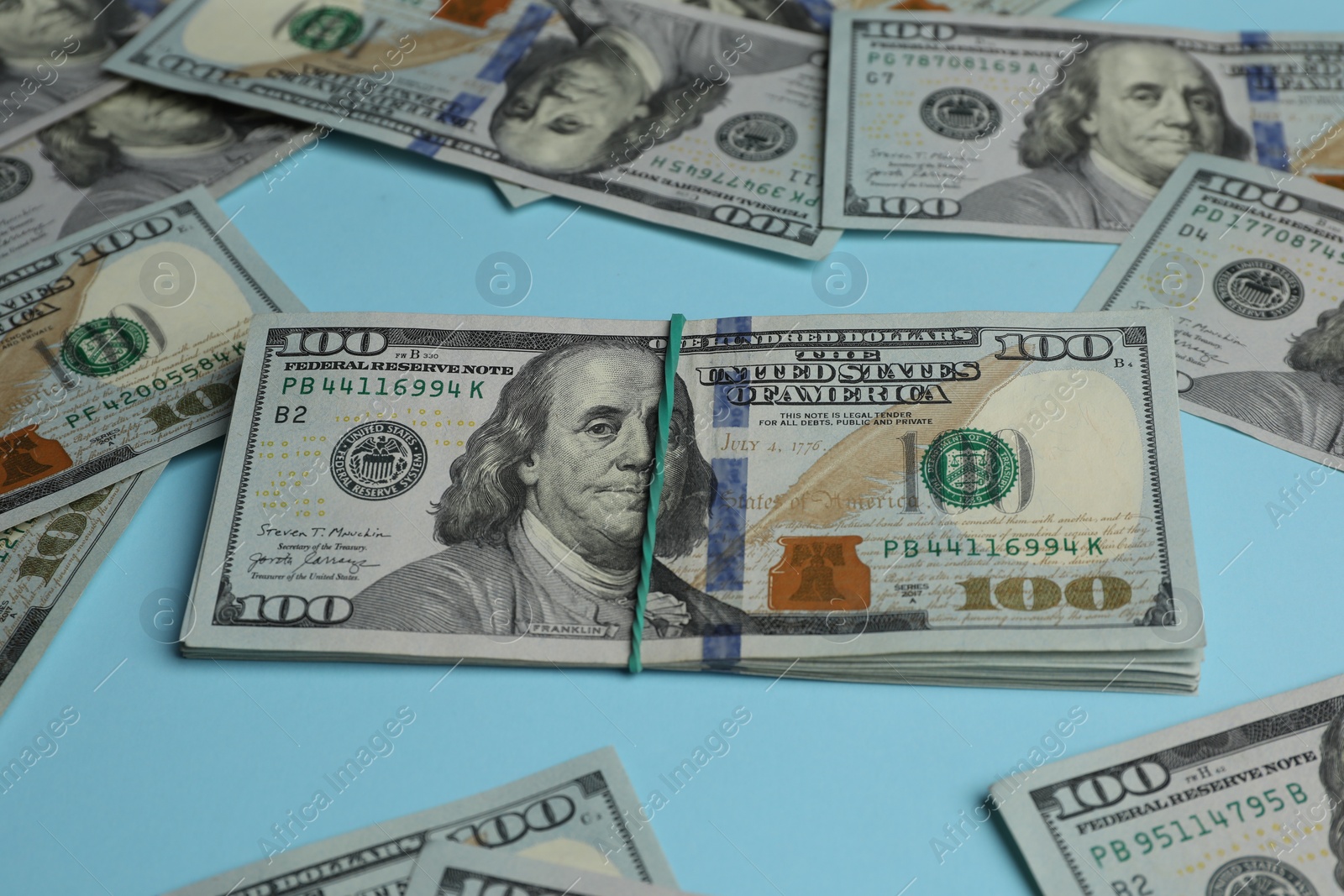 Photo of Money exchange. Dollar banknotes on light blue background, closeup