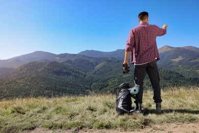 Photo of Tourist with hiking equipment and binoculars in mountains, back view