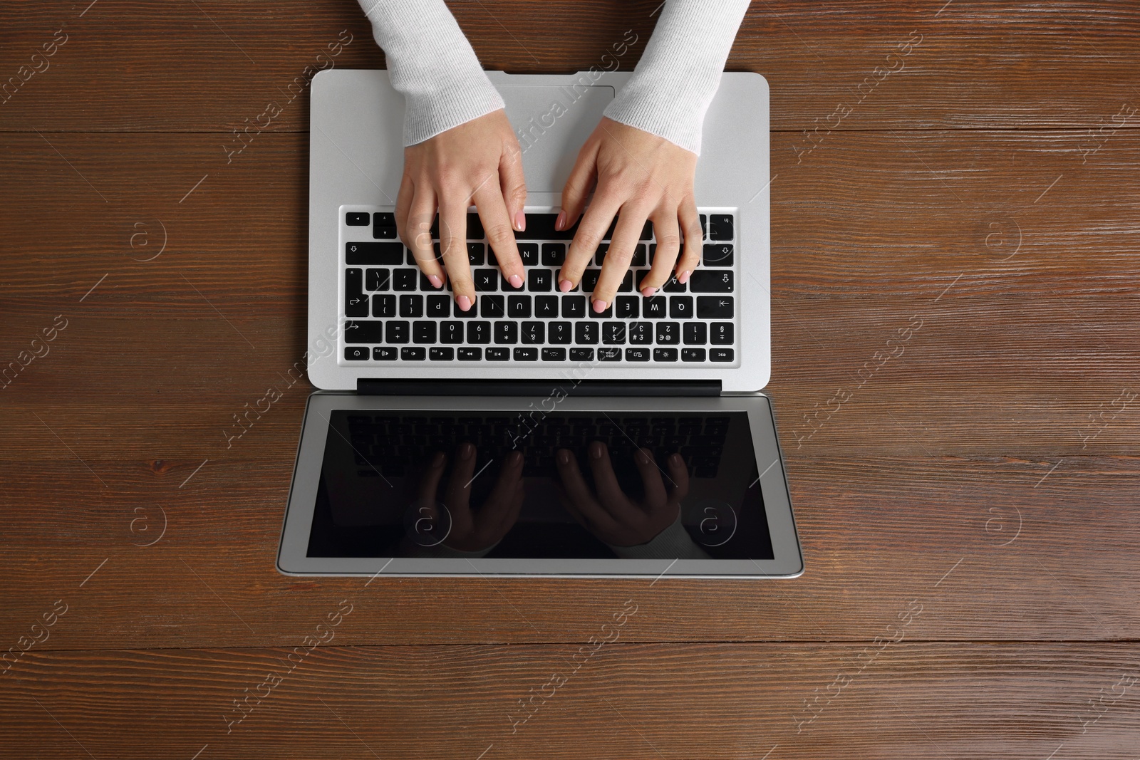 Photo of Woman working with laptop at wooden table, top view