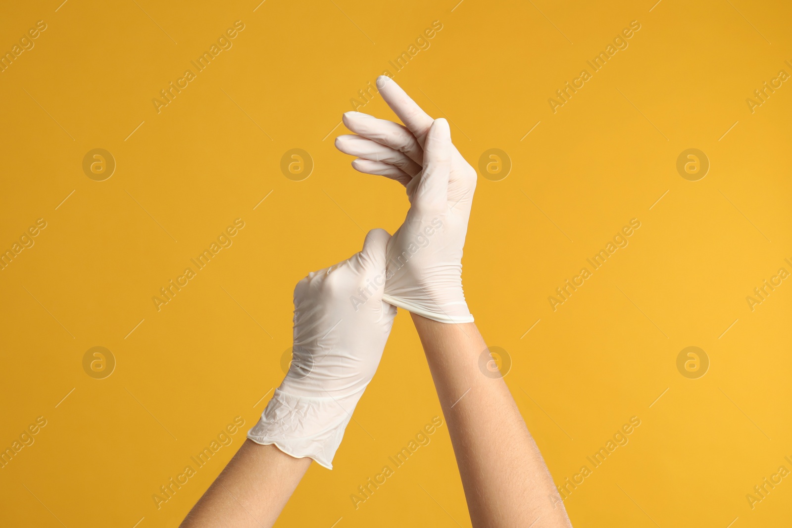 Photo of Doctor wearing medical gloves on yellow background, closeup