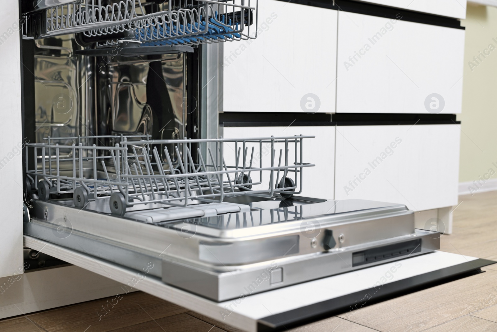 Photo of Open clean empty dishwasher in kitchen. Home appliance