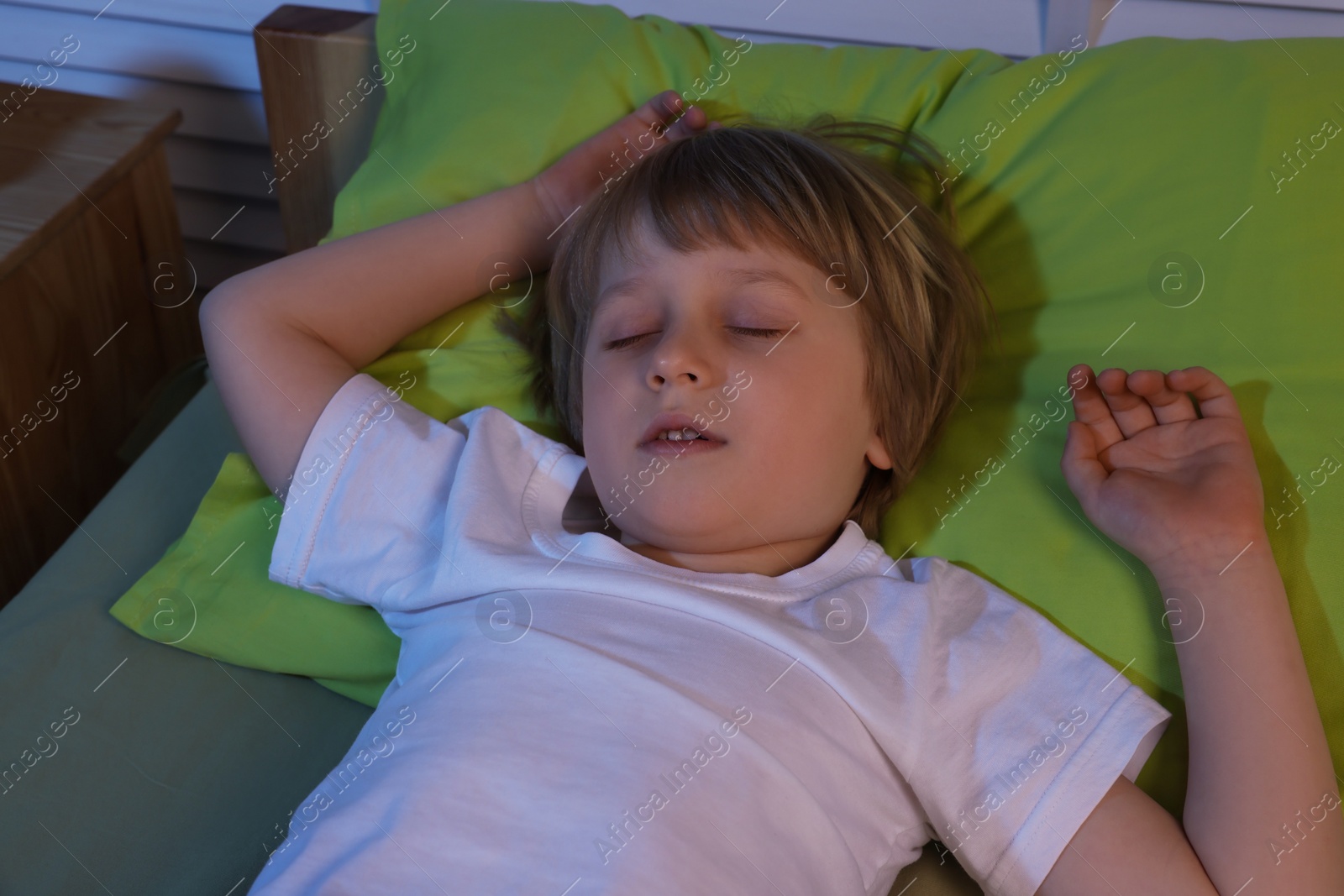 Photo of Little boy snoring while sleeping on bed at night