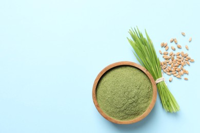 Photo of Wheat grass powder in bowl, seeds and fresh sprouts on light blue background, flat lay. Space for text