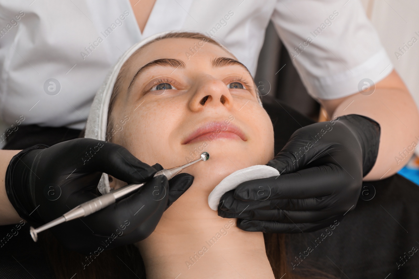 Photo of Cosmetologist using scrubber, closeup. Client having cleansing procedure