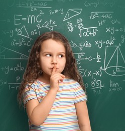 Cute little girl near green chalkboard with different formulas