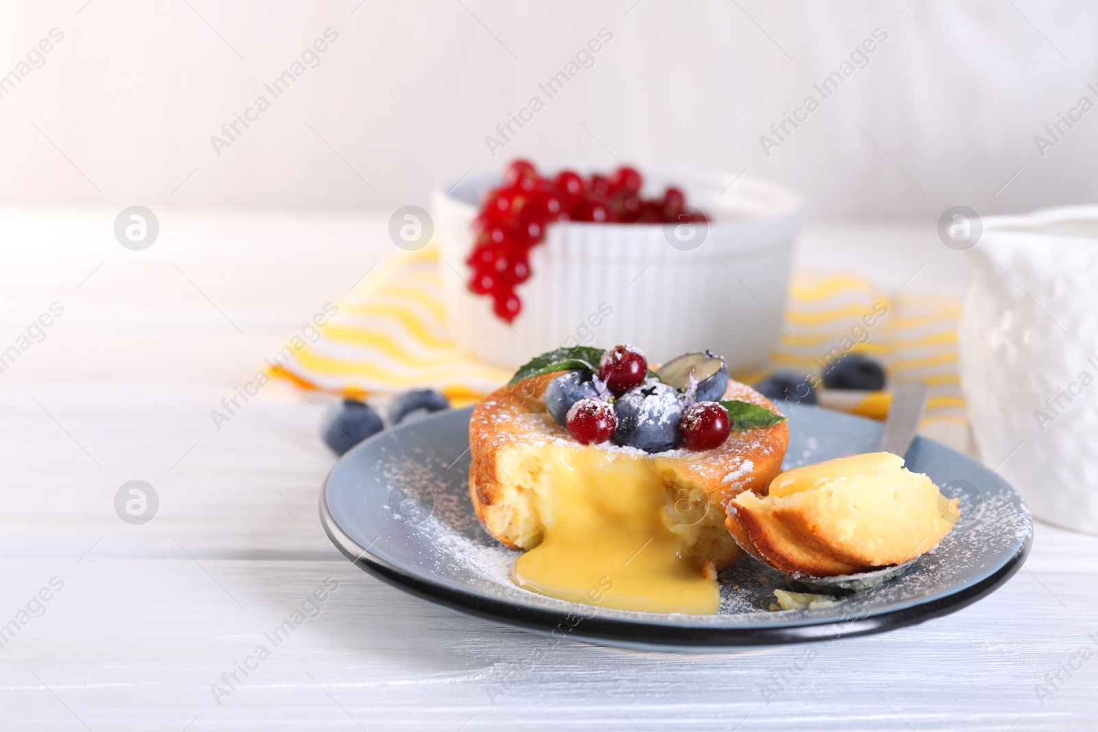 Photo of Tasty vanilla fondant with white chocolate and berries on light wooden table. Space for text