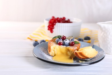 Tasty vanilla fondant with white chocolate and berries on light wooden table. Space for text