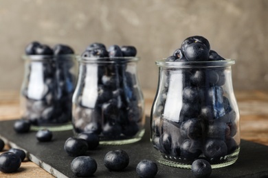 Photo of Jars of fresh acai berries on black board, closeup. Space for text