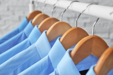 Rack with clean clothes on hangers after dry-cleaning, closeup