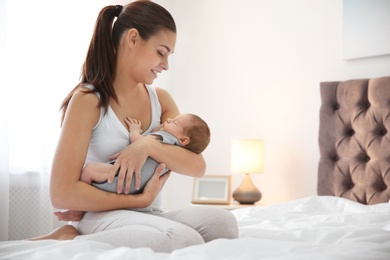 Photo of Young woman with her newborn baby in bedroom. Space for text