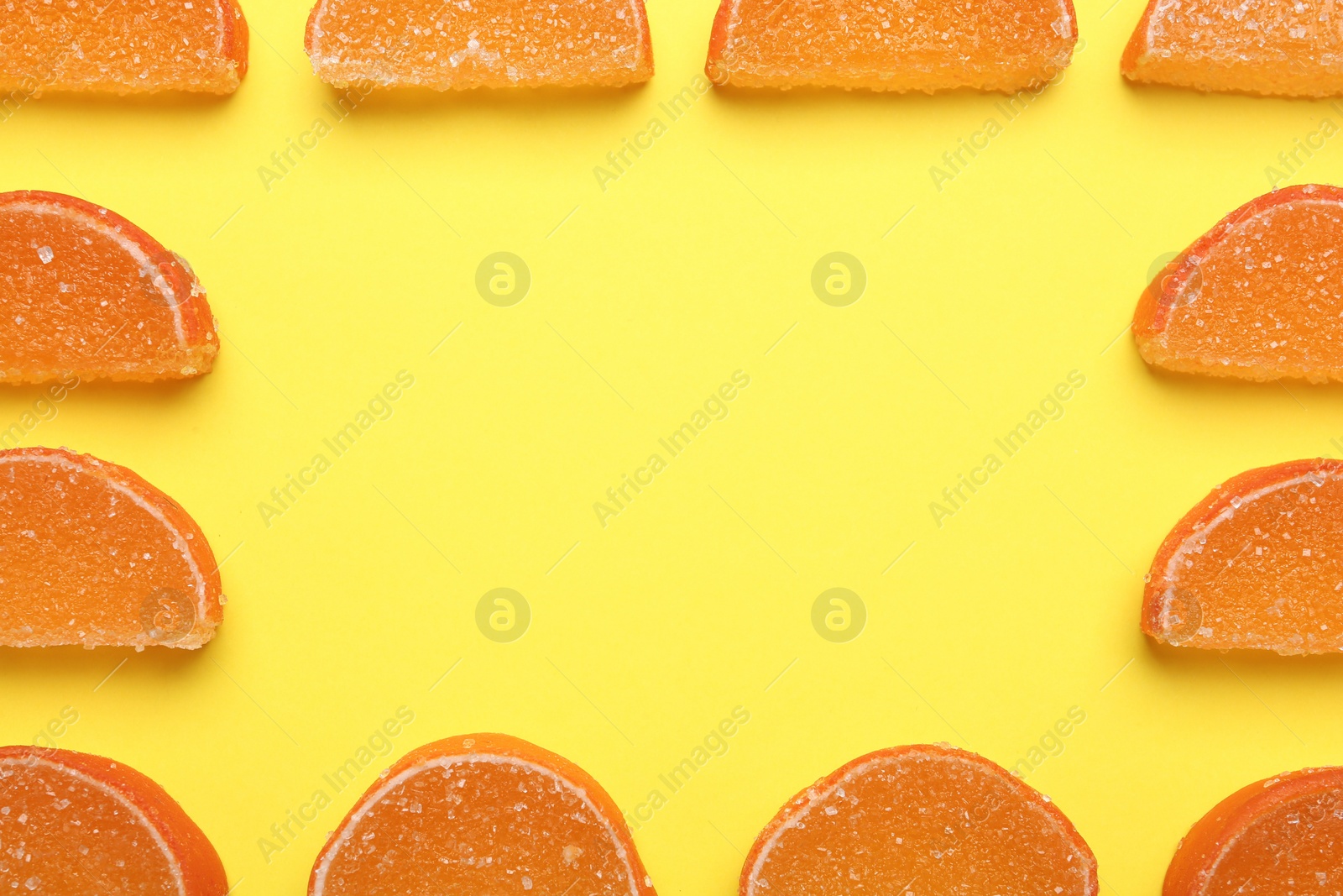 Photo of Frame made with orange marmalade candies on yellow background, flat lay. Space for text