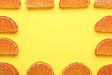 Frame made with orange marmalade candies on yellow background, flat lay. Space for text