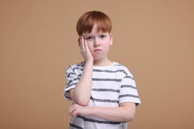 Photo of Portrait of sad little boy on beige background