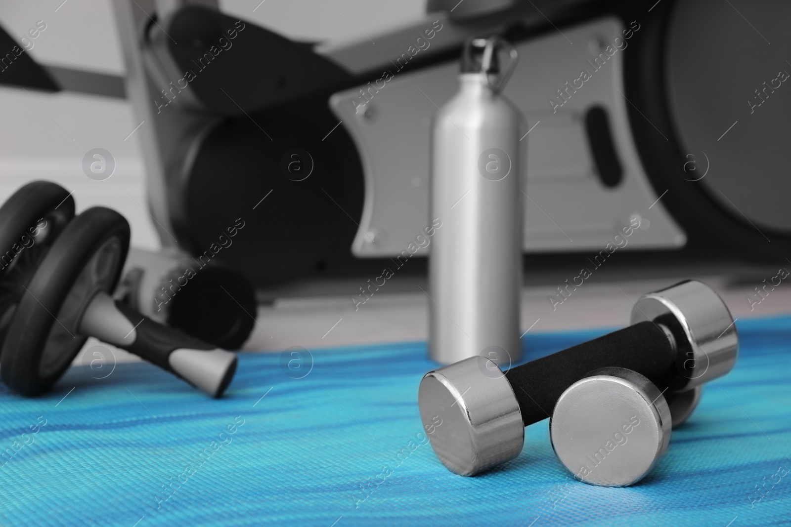 Photo of Dumbbells and sport equipment near elliptical machine in gym