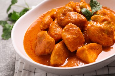 Photo of Bowl of delicious chicken curry on light grey table, closeup