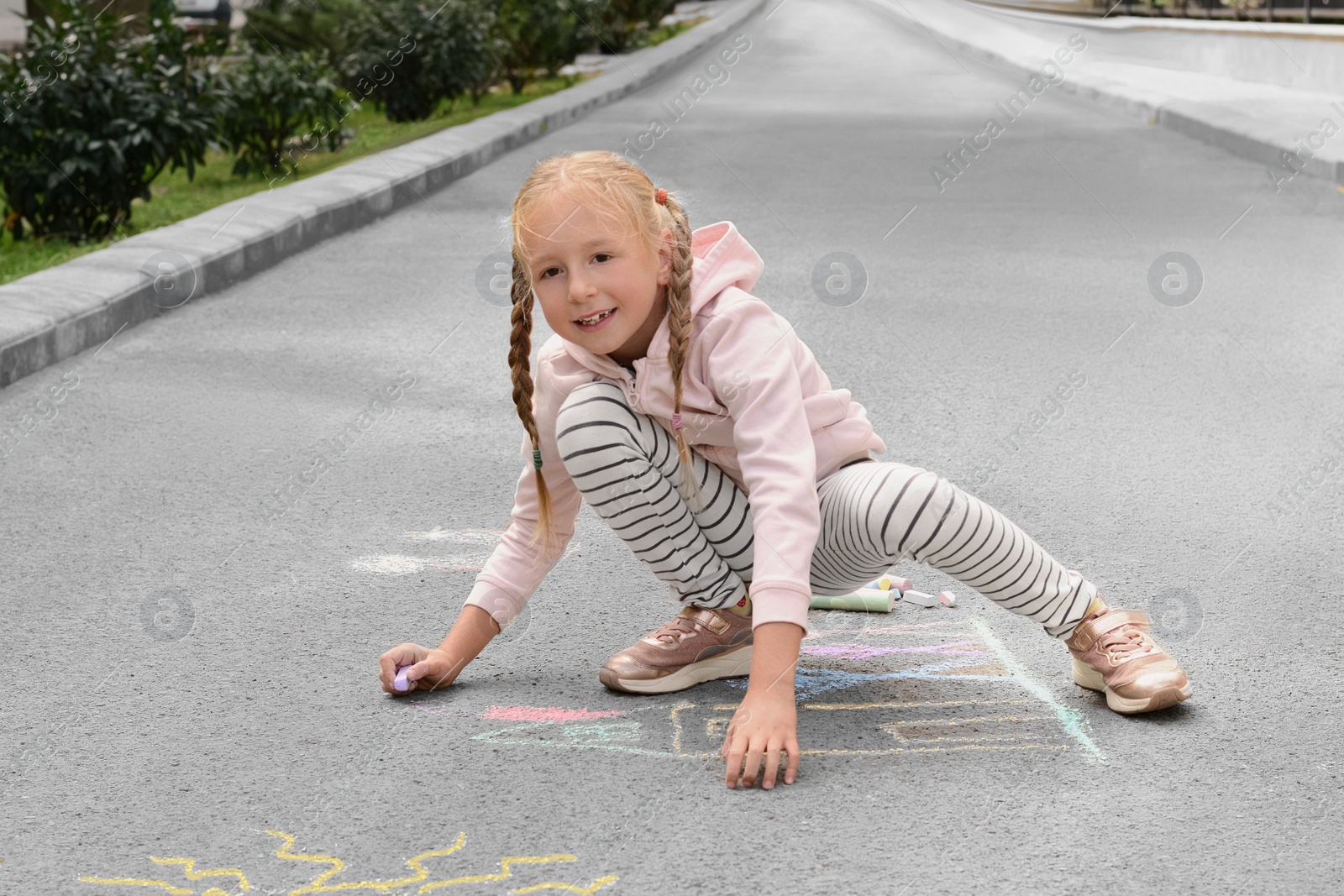 Photo of Little child drawing happy family with chalk on asphalt