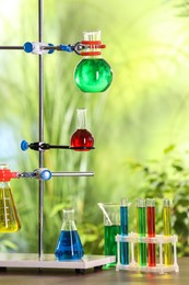 Photo of Laboratory glassware with colorful liquids on table against blurred background