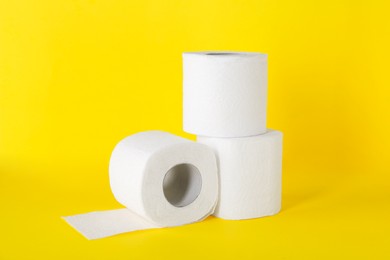 Photo of Many soft toilet paper rolls on yellow background