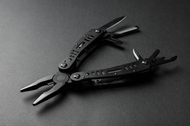 Photo of Compact portable multitool on black background, closeup