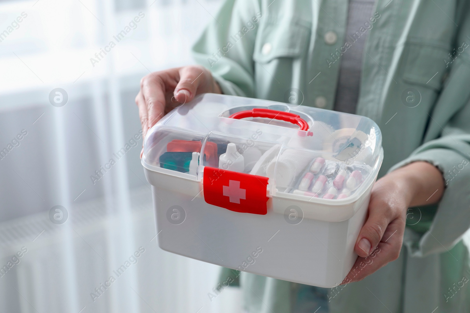 Photo of Woman holding first aid kit indoors, closeup. Space for text