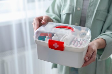 Photo of Woman holding first aid kit indoors, closeup. Space for text