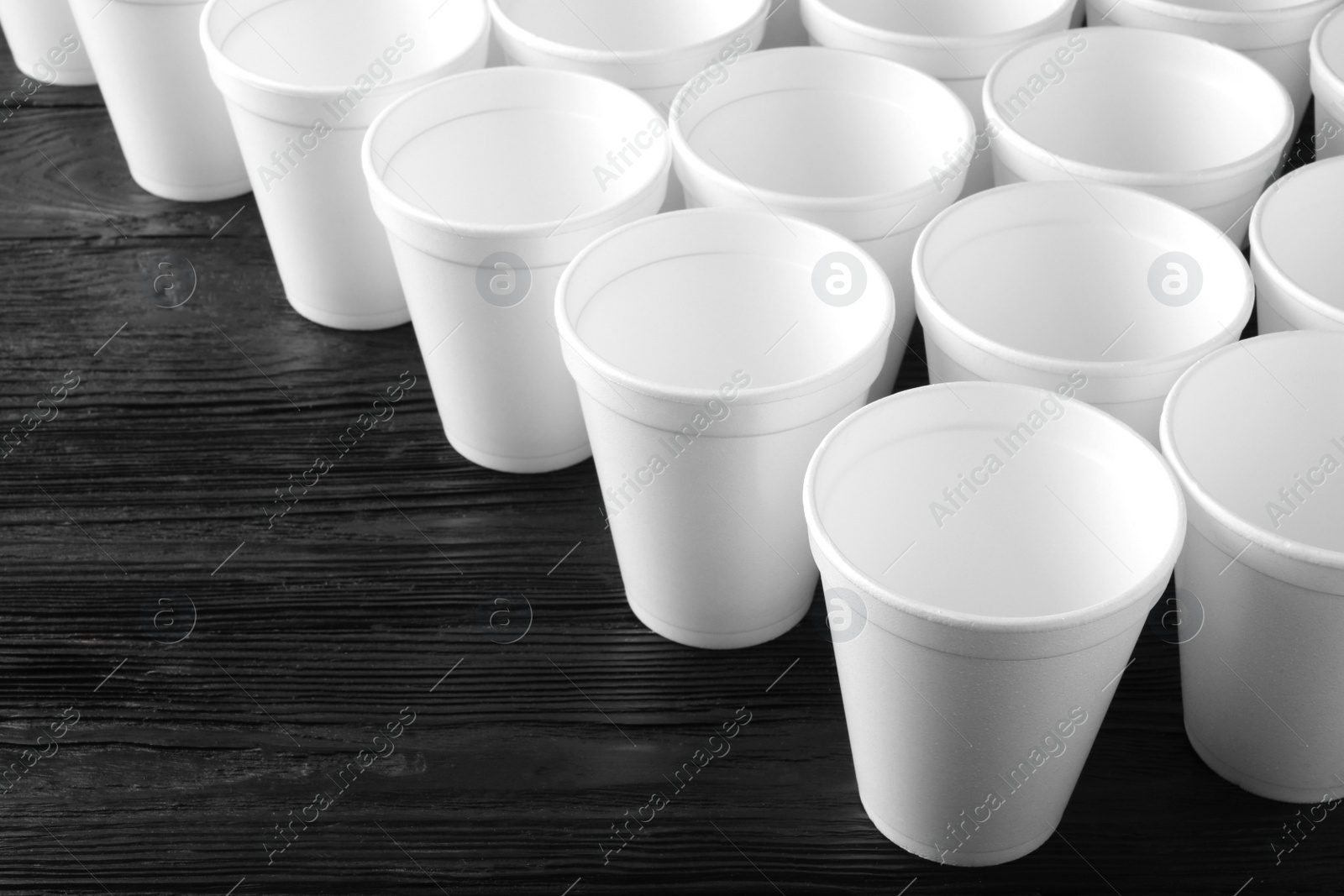 Photo of Many white styrofoam cups on black wooden table, closeup