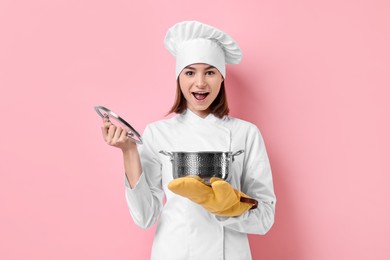 Professional chef with cooking pot on pink background