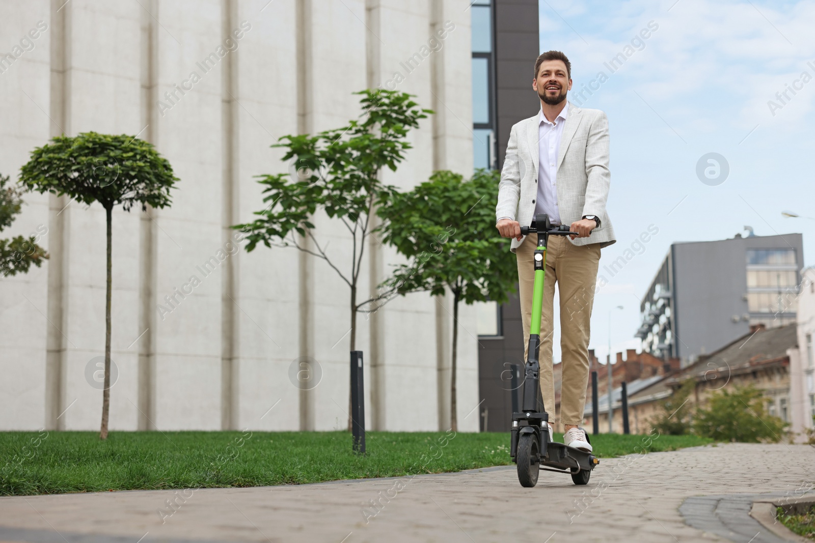 Photo of Businessman riding modern kick scooter on city street, space for text