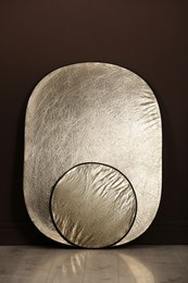 Photo of Studio reflectors near brown wall in room. Professional photographer's equipment