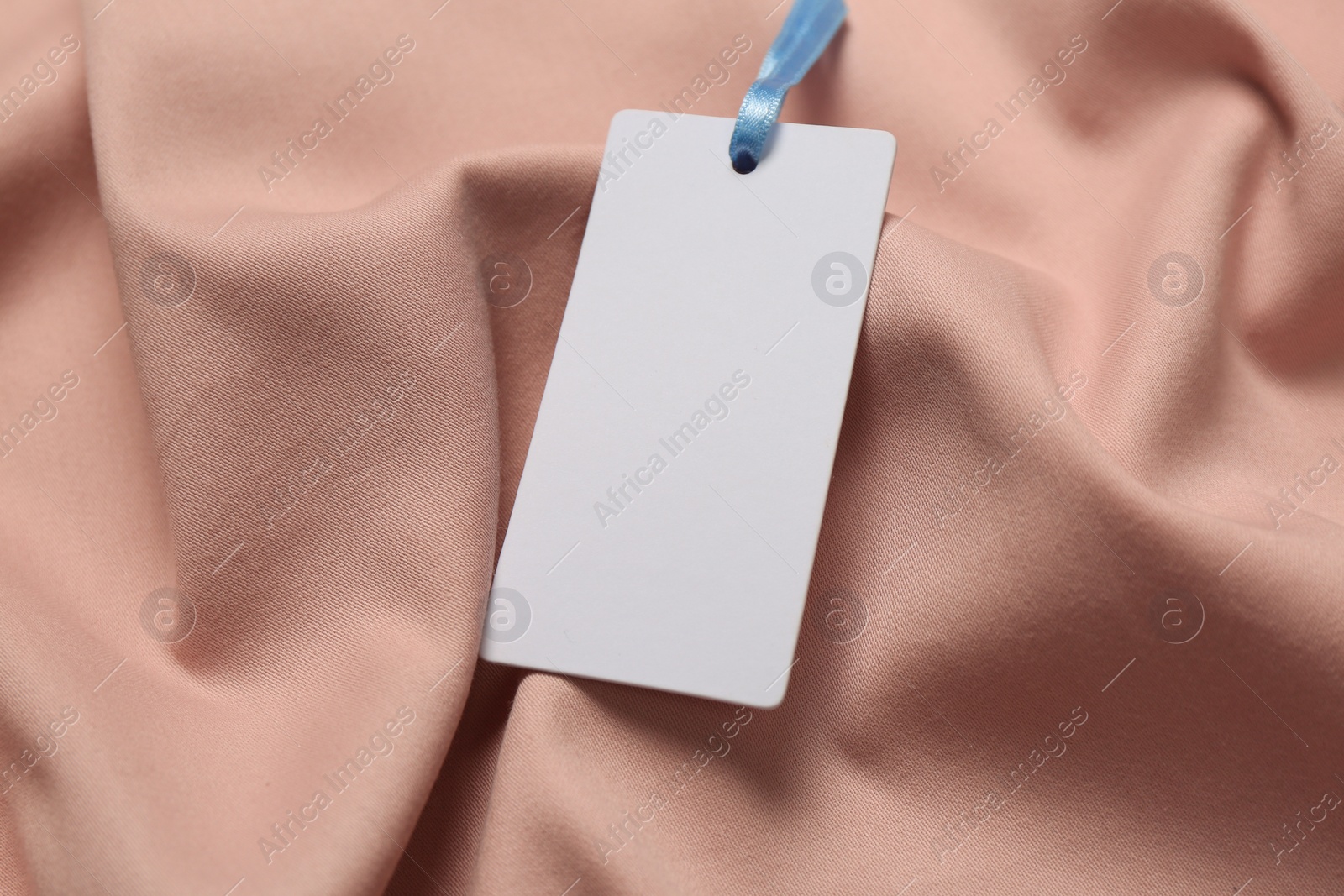 Photo of Blank white tag on pink fabric. Space or text