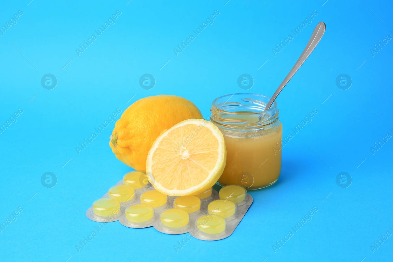 Photo of Blister with cough drops, fresh lemons and honey on light blue background