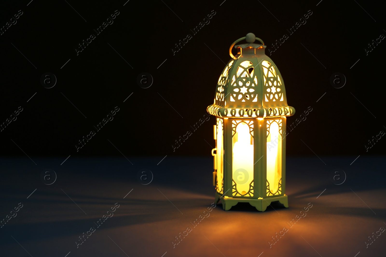 Photo of Decorative Arabic lantern on table against dark background. Space for text