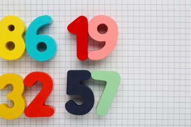 Photo of Colorful numbers on sheet of grid paper, flat lay. Space for text