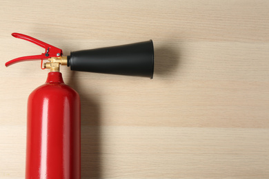 Photo of Fire extinguisher on wooden background, top view. Space for text